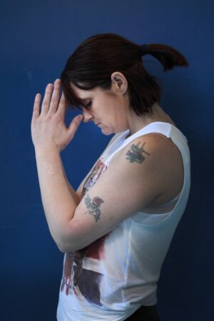 side view of woman with tattoos in standing yoga pose