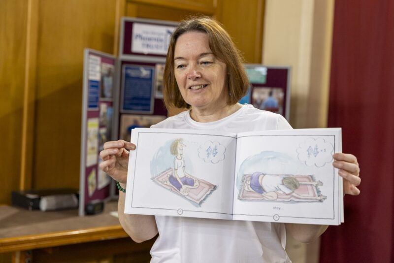 Woman with brown hair showing a book open at yoga pictures